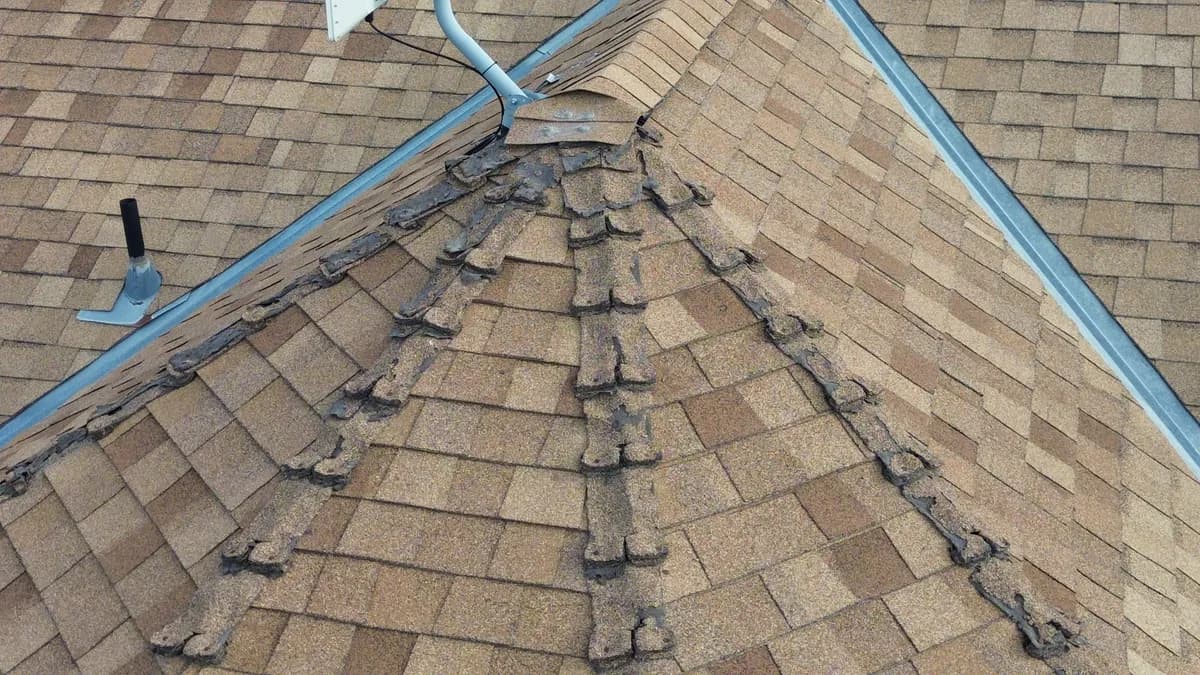 Storm-damaged shingle roof section illustrating when repair may no longer be enough