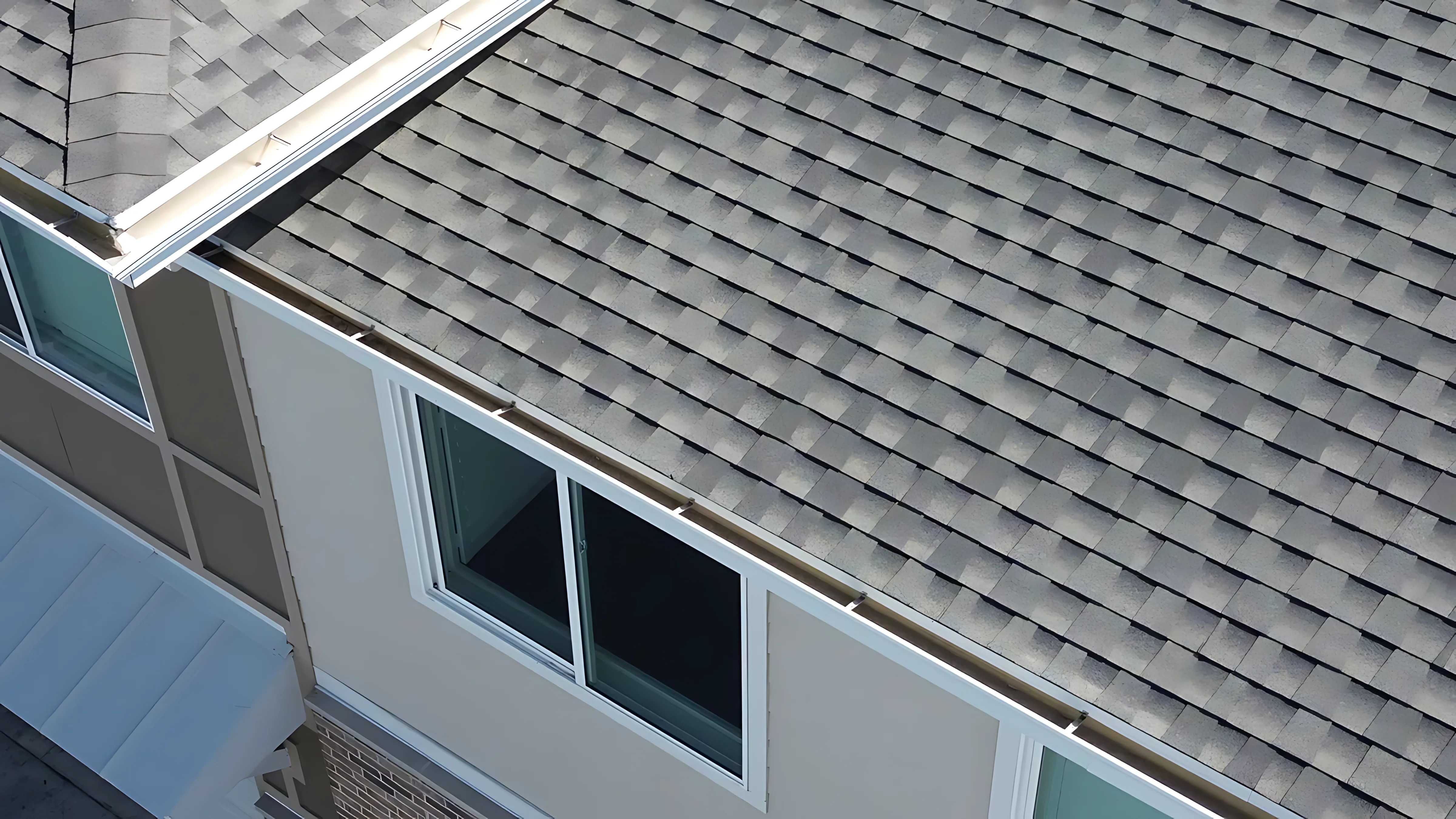 Close-up of asphalt shingles showing UV degradation and granule loss on a west-facing slope